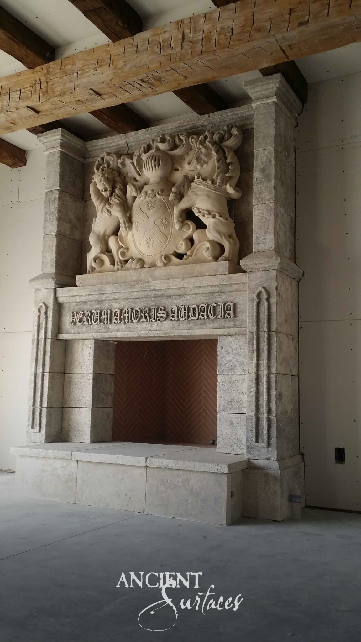 Monumental reclaimed limestone chimneypiece with a carved heraldic overmantel, inscribed frieze and herringbone brick firebox