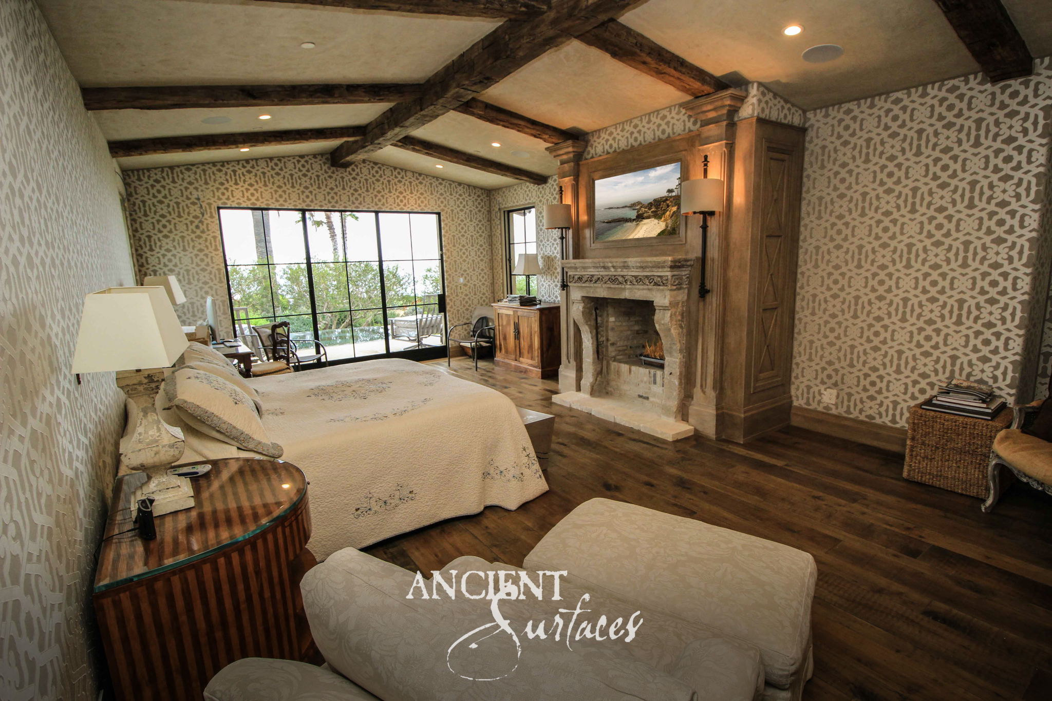 Carved reclaimed limestone fireplace mantel with curved console jambs set into a timber paneled chimney breast in a beamed bedroom